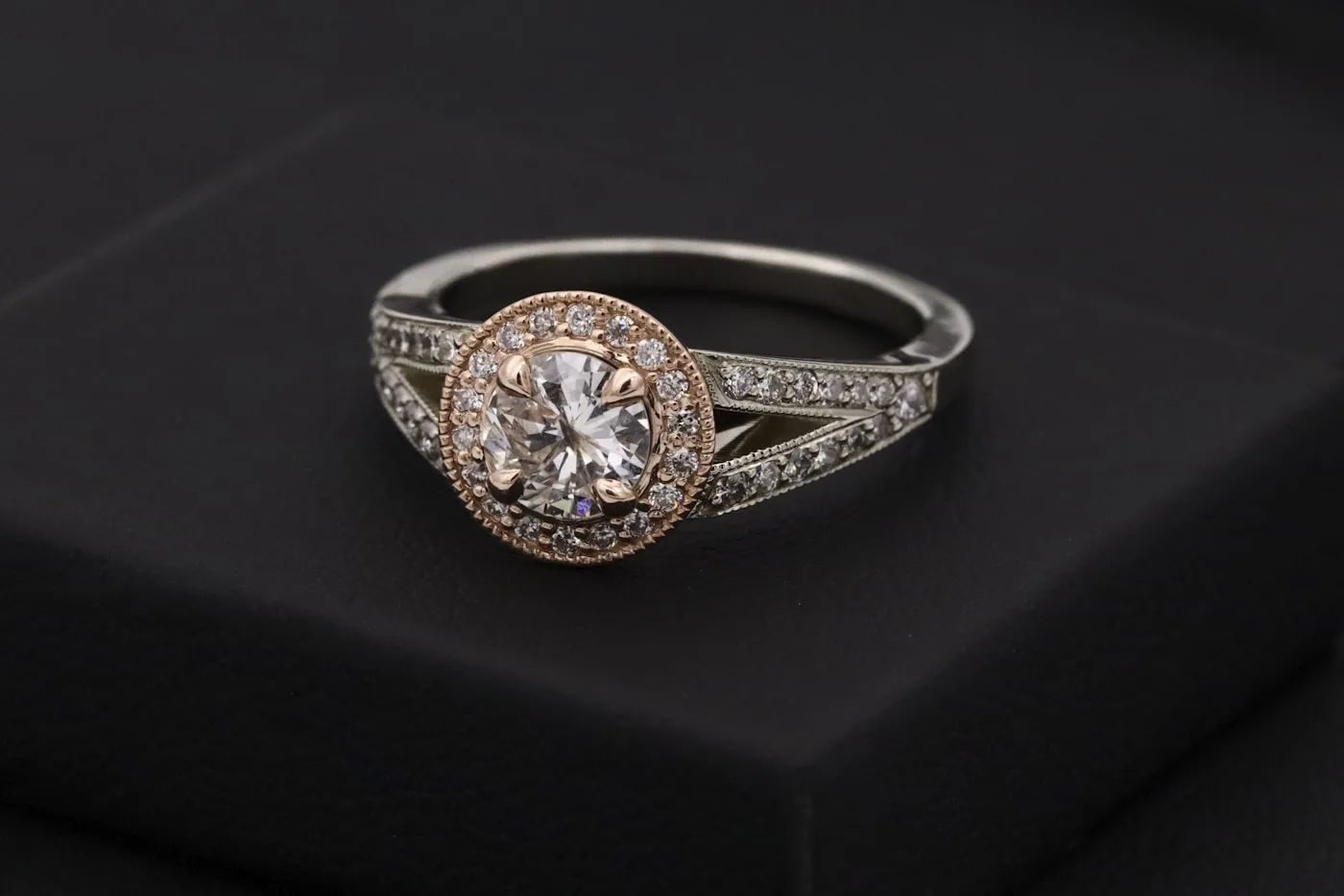 Rose gold and white diamond ring shown against a dark surface